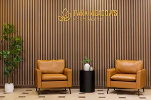 A sign on the wall that says Park Meadows with two chairs below it